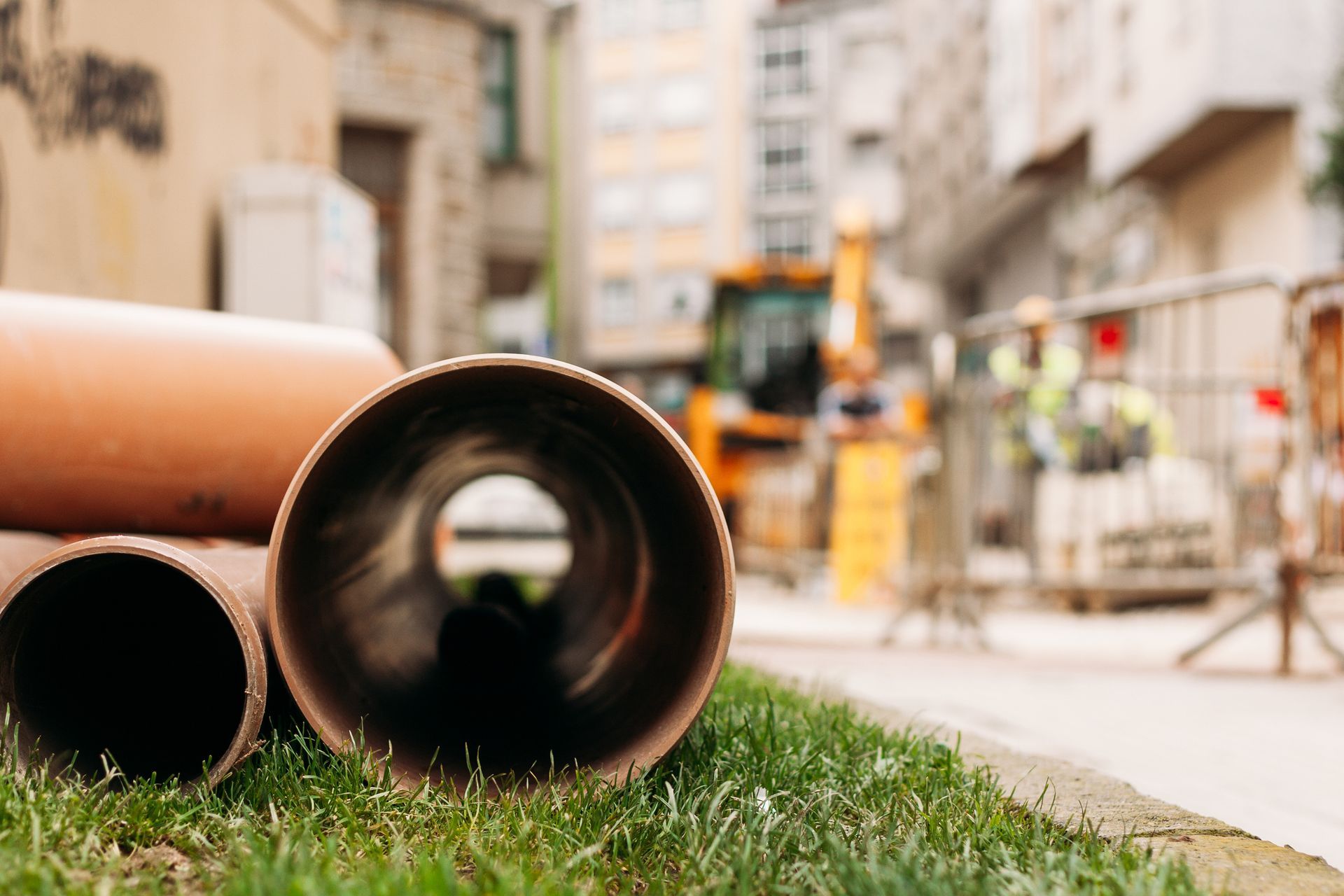 A stack of pipes sitting on top of a lush green field.