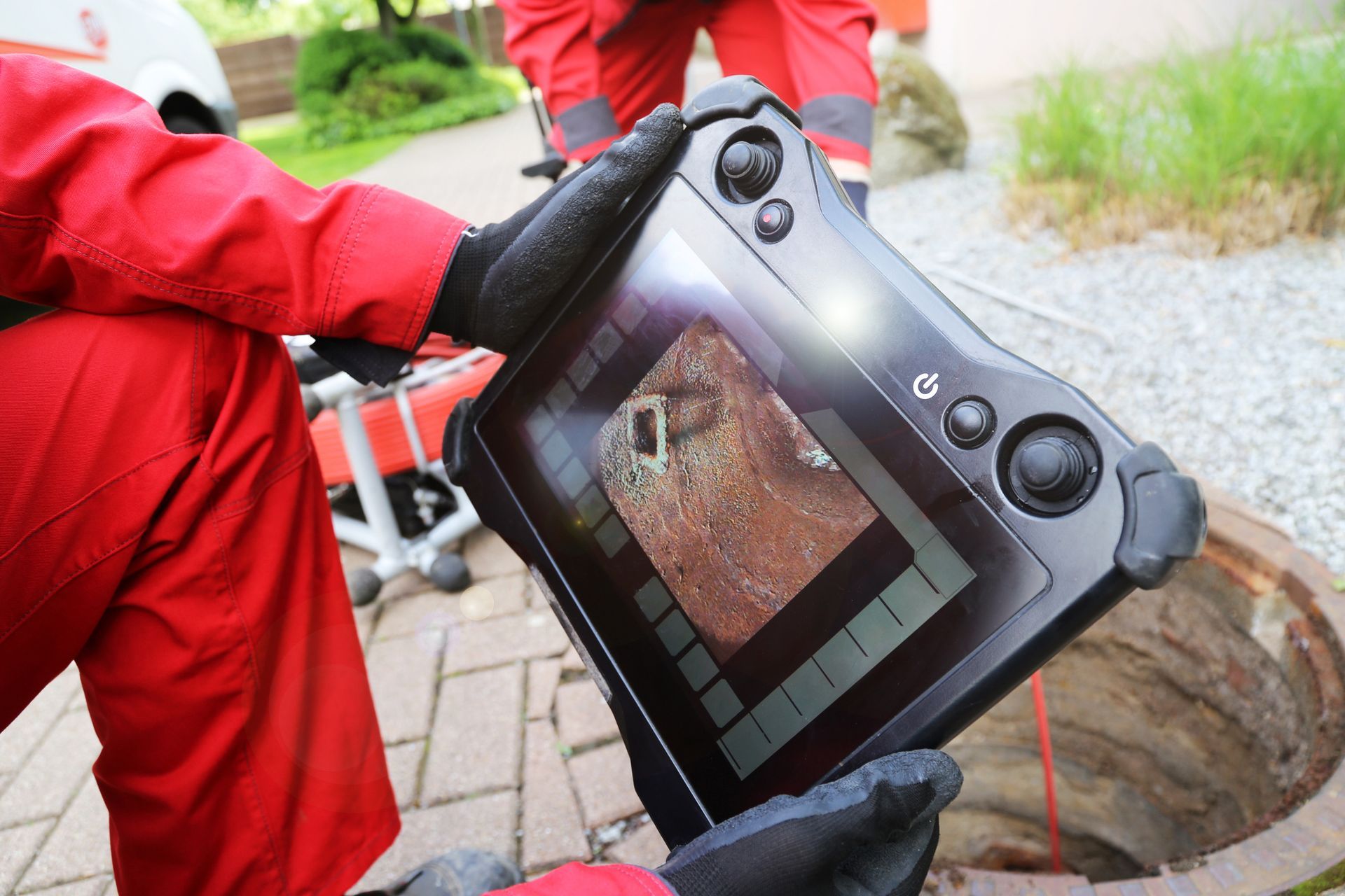 A person is holding a tablet with a picture of a manhole cover on it.