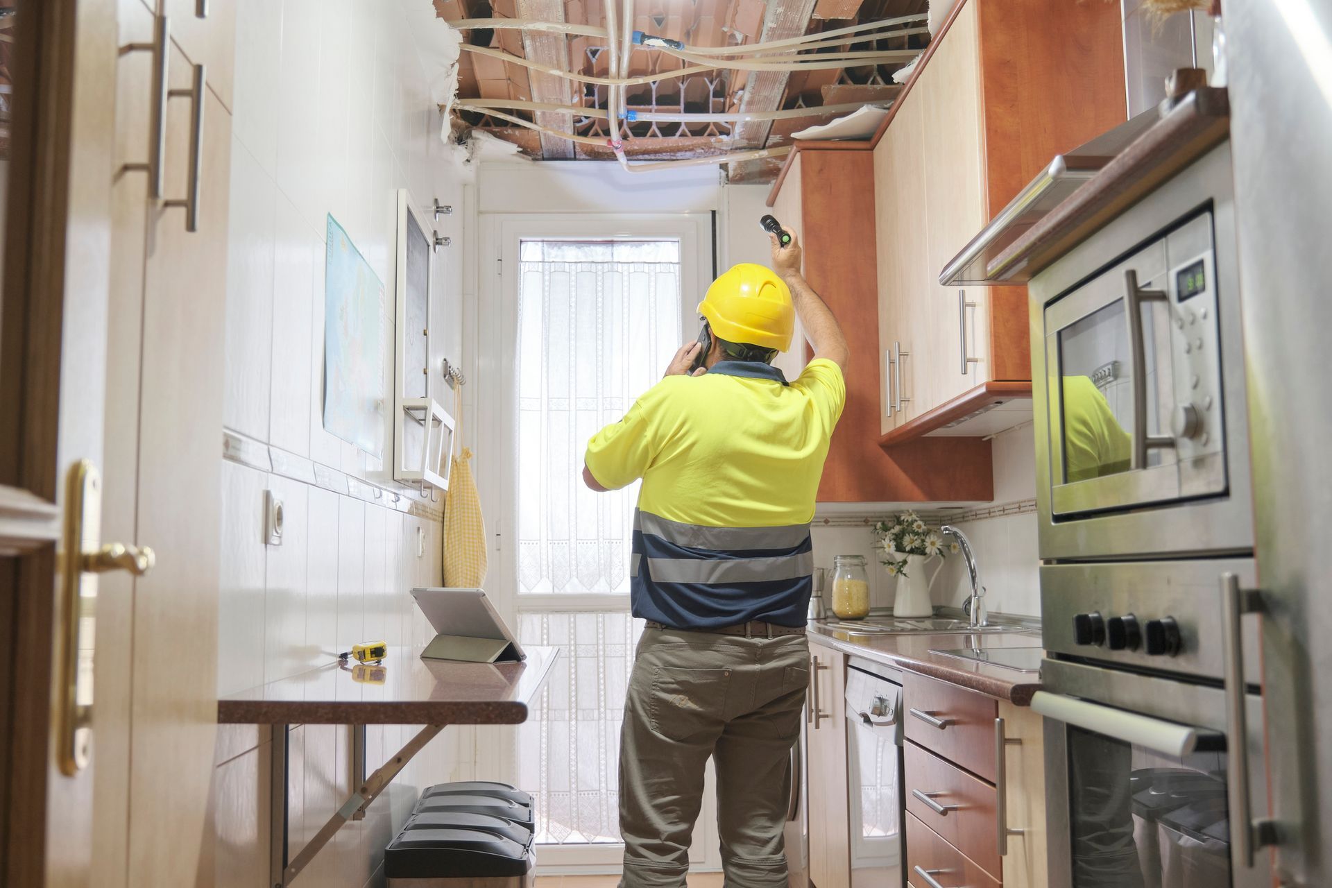 A man is standing in a kitchen looking at the ceiling.