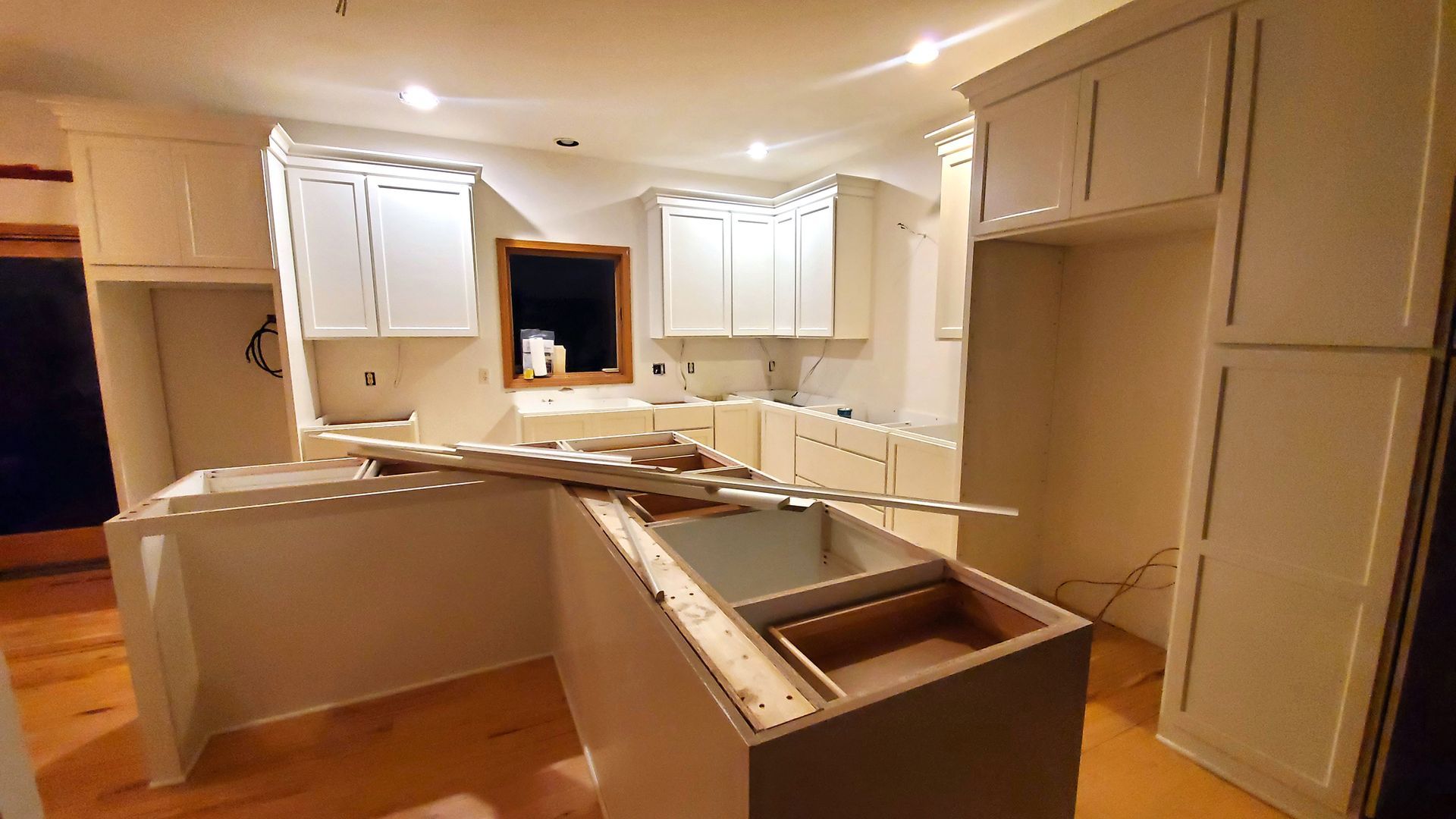 A kitchen under construction with white cabinets and a sink.