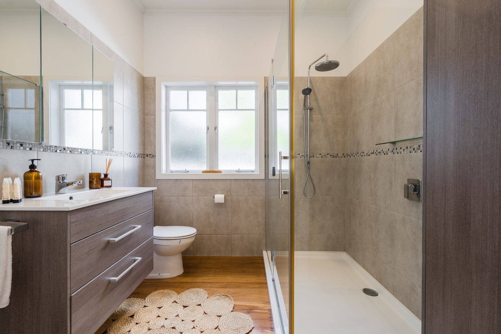 A bathroom with a toilet , sink , shower and window.