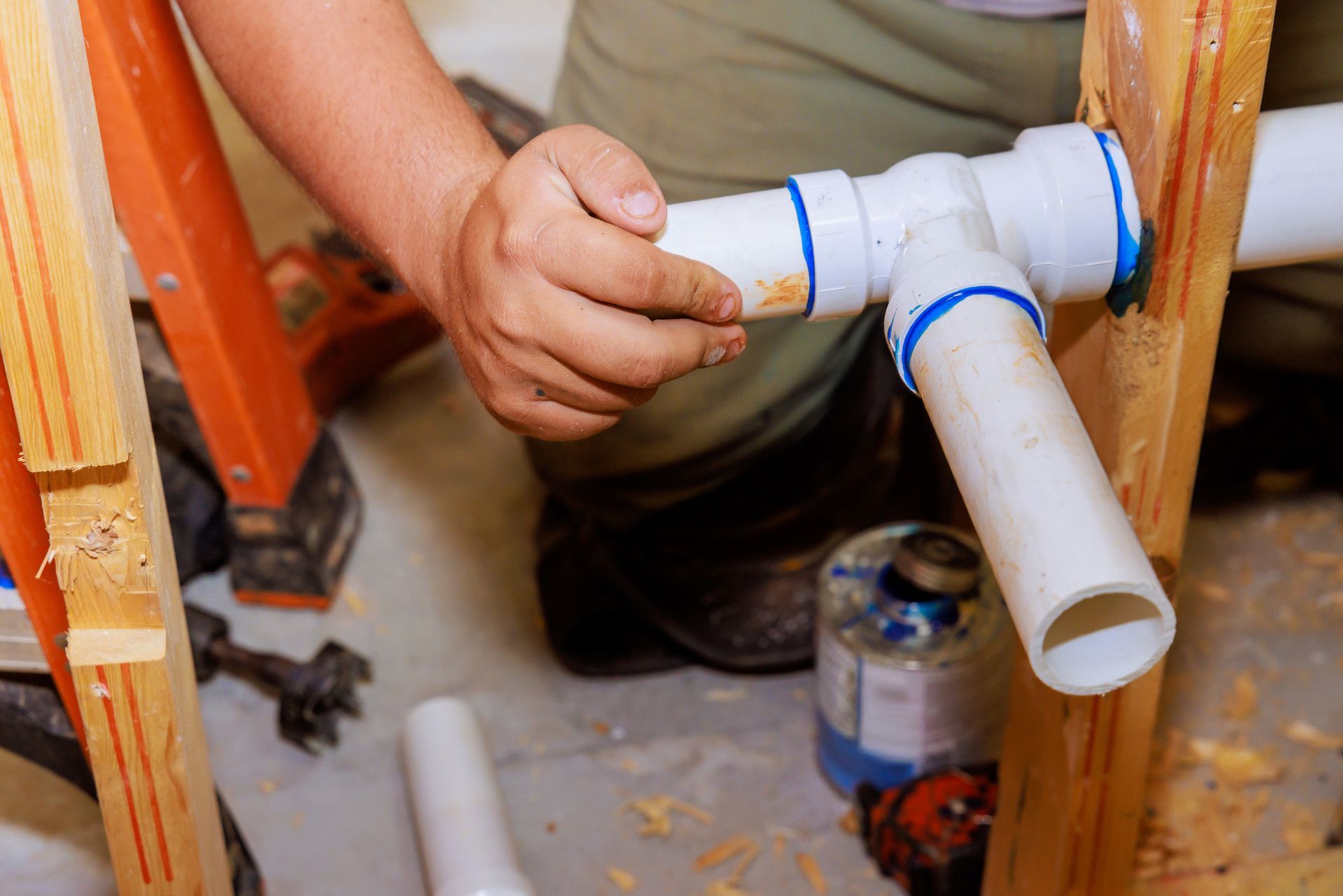 A plumber is working on a pipe in a basement.