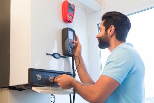 A man is fixing a boiler with a tool.
