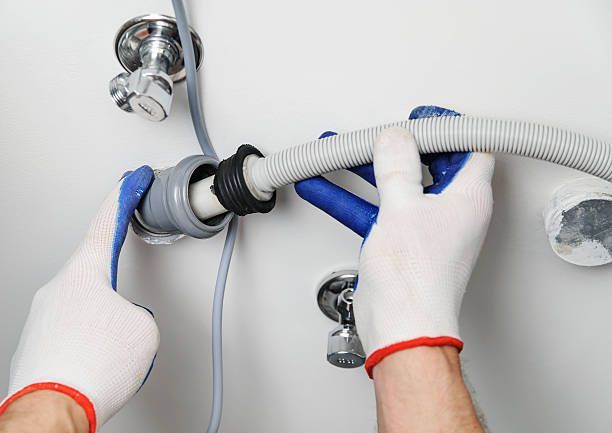 A person is connecting a hose to a faucet with a wrench.