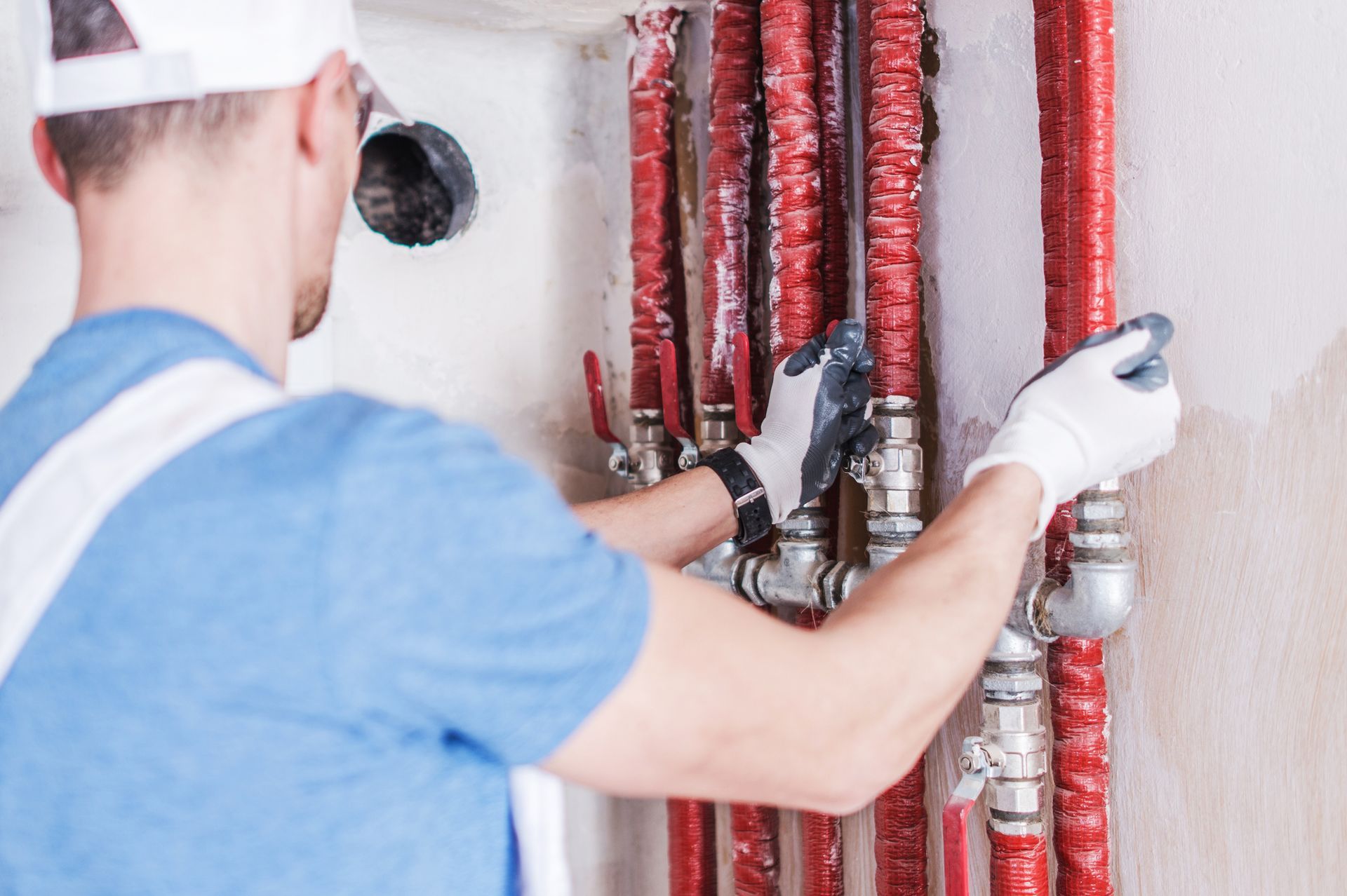 A man is working on a water pipe with a wrench.