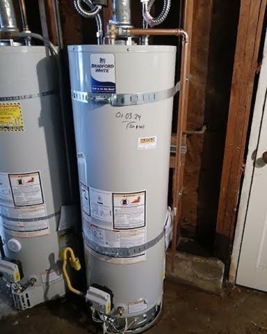 Two water heaters are sitting next to each other in a basement.