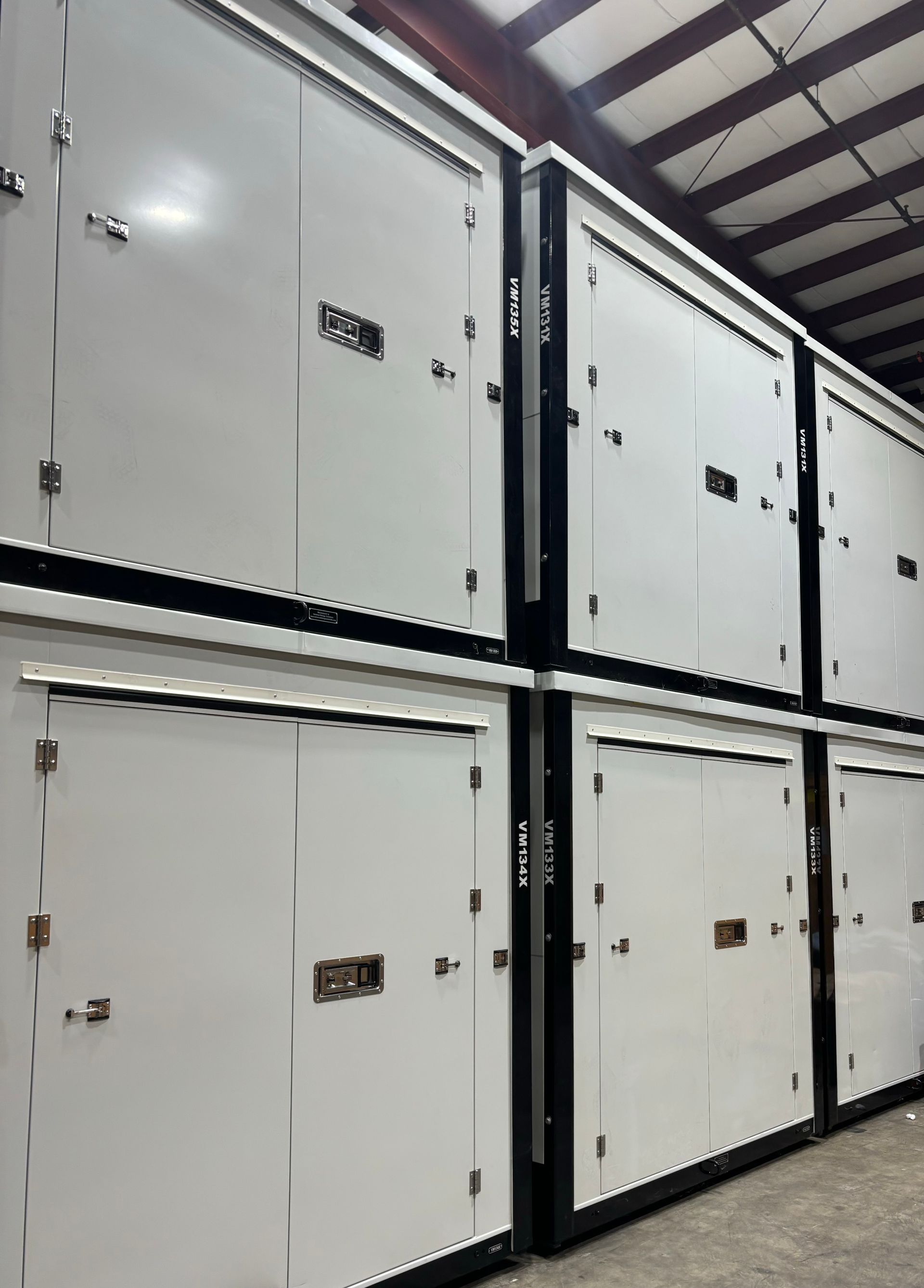 Rows of white industrial storage cabinets or electrical enclosures in a warehouse interior.