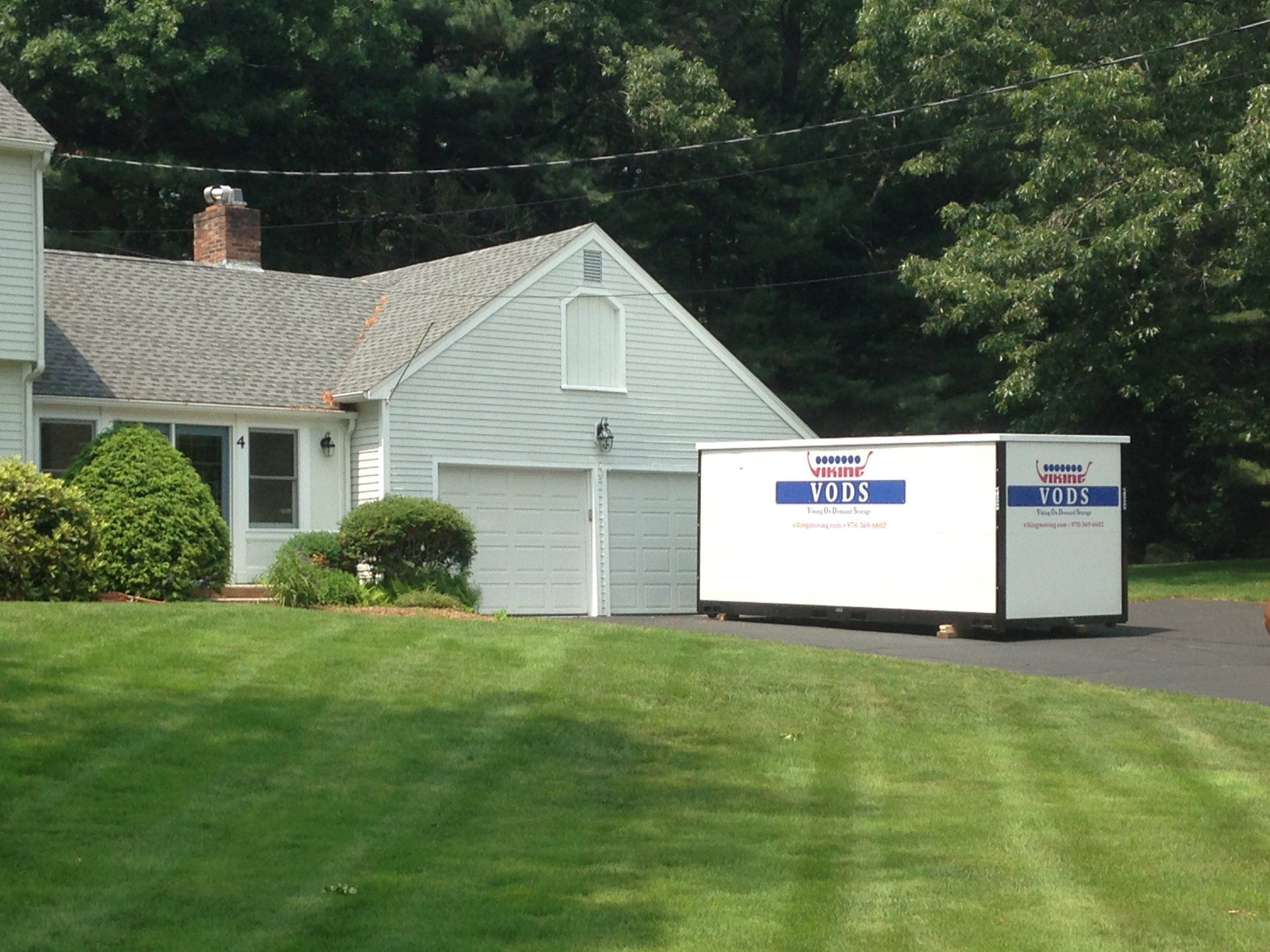 Large suburban home with VODS Portable Storage Container in driveway.