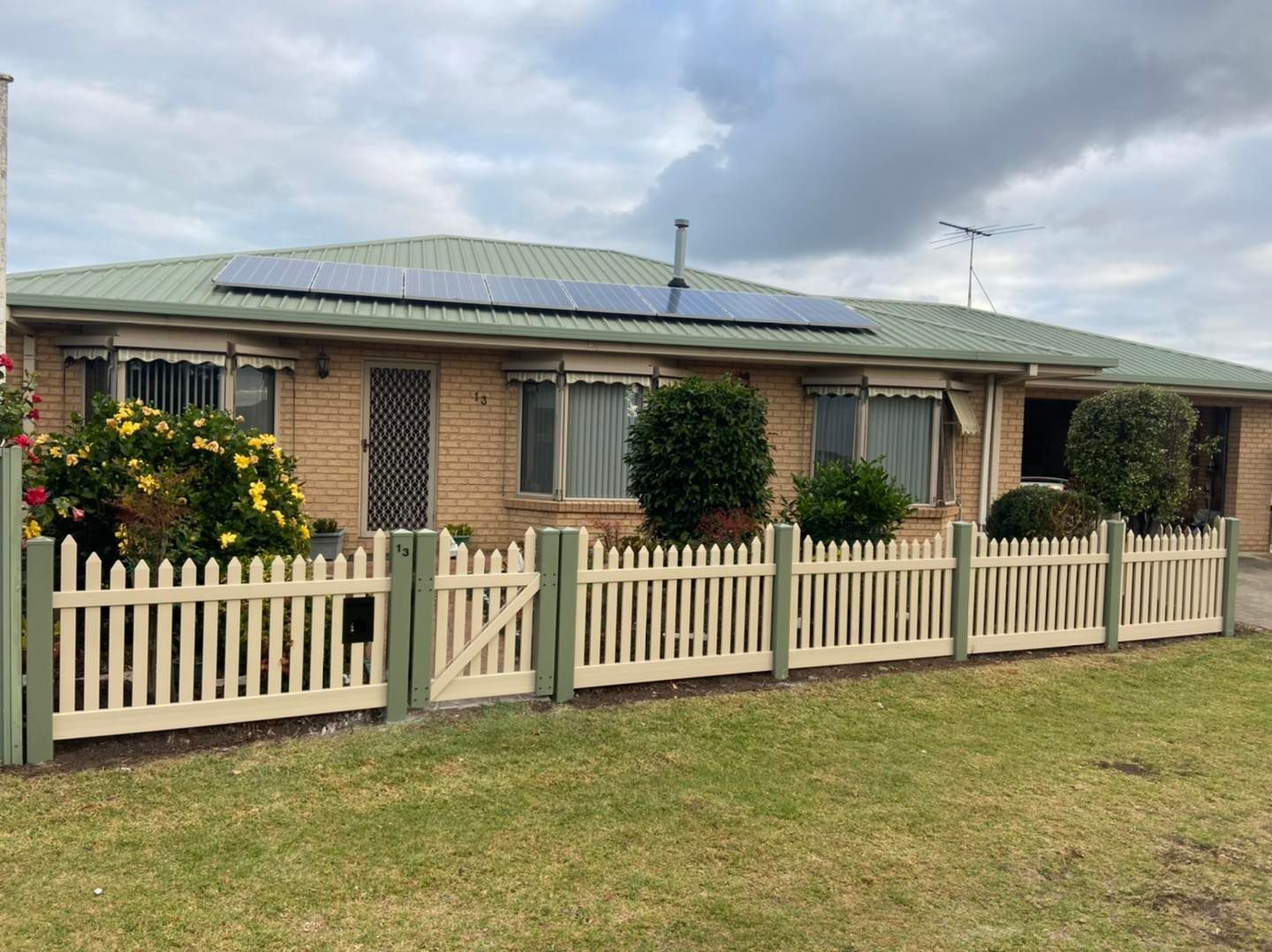 A house with a white picket fence and solar panels on the roof.  — Talking Fences In Portarlington, VIC