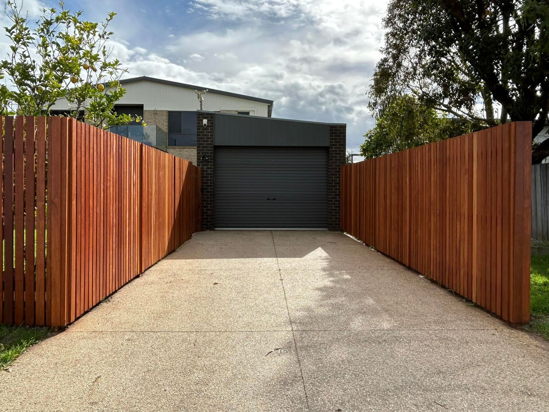 A wooden fence surrounds a driveway leading to a garage.  — Talking Fences In Portarlington, VIC