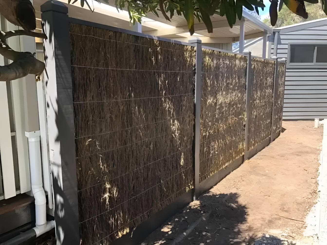 A fence made of straw is sitting in front of a house.  — Talking Fences In Portarlington, VIC