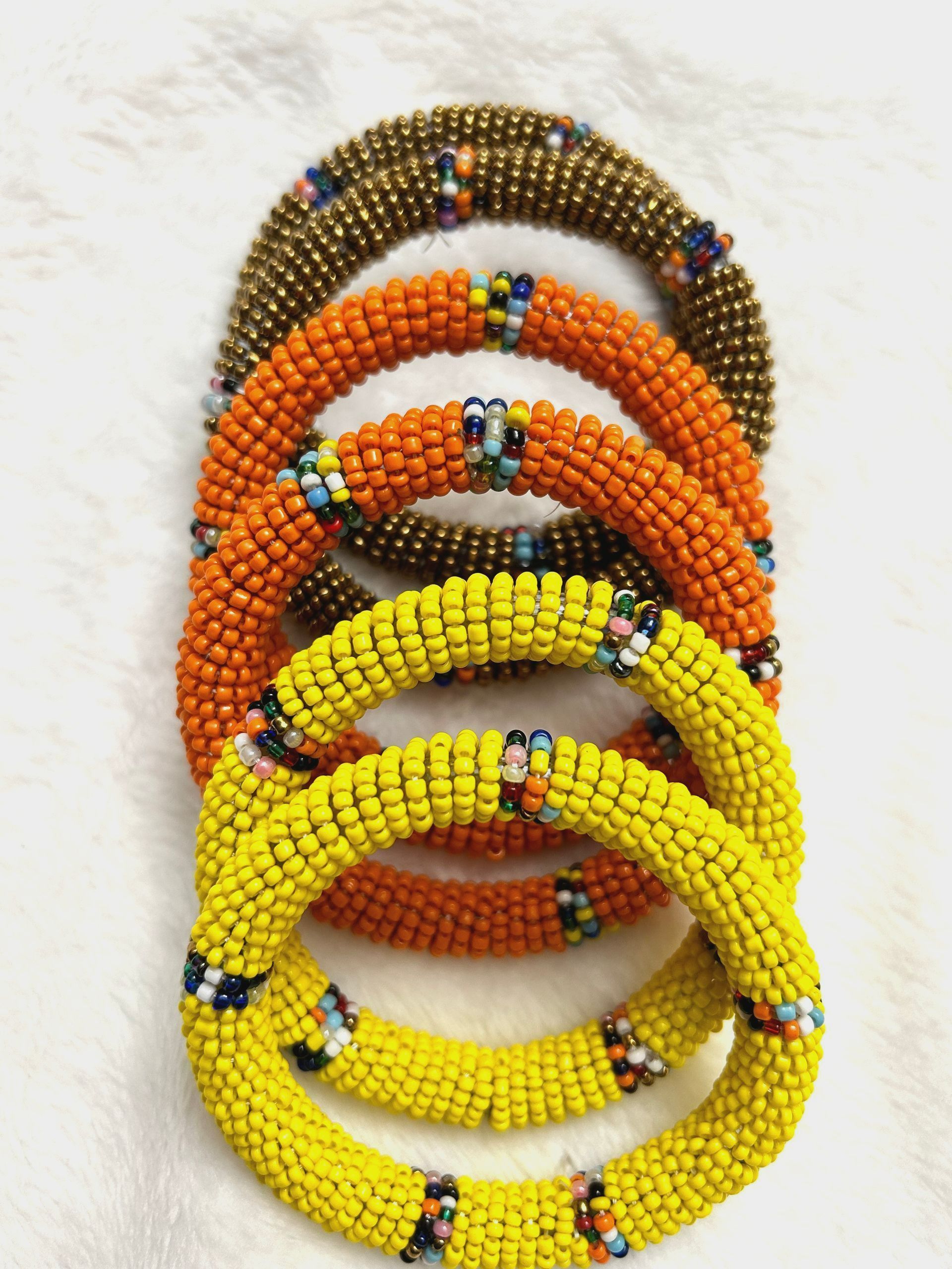Five beaded bracelets in gold, orange, and yellow.