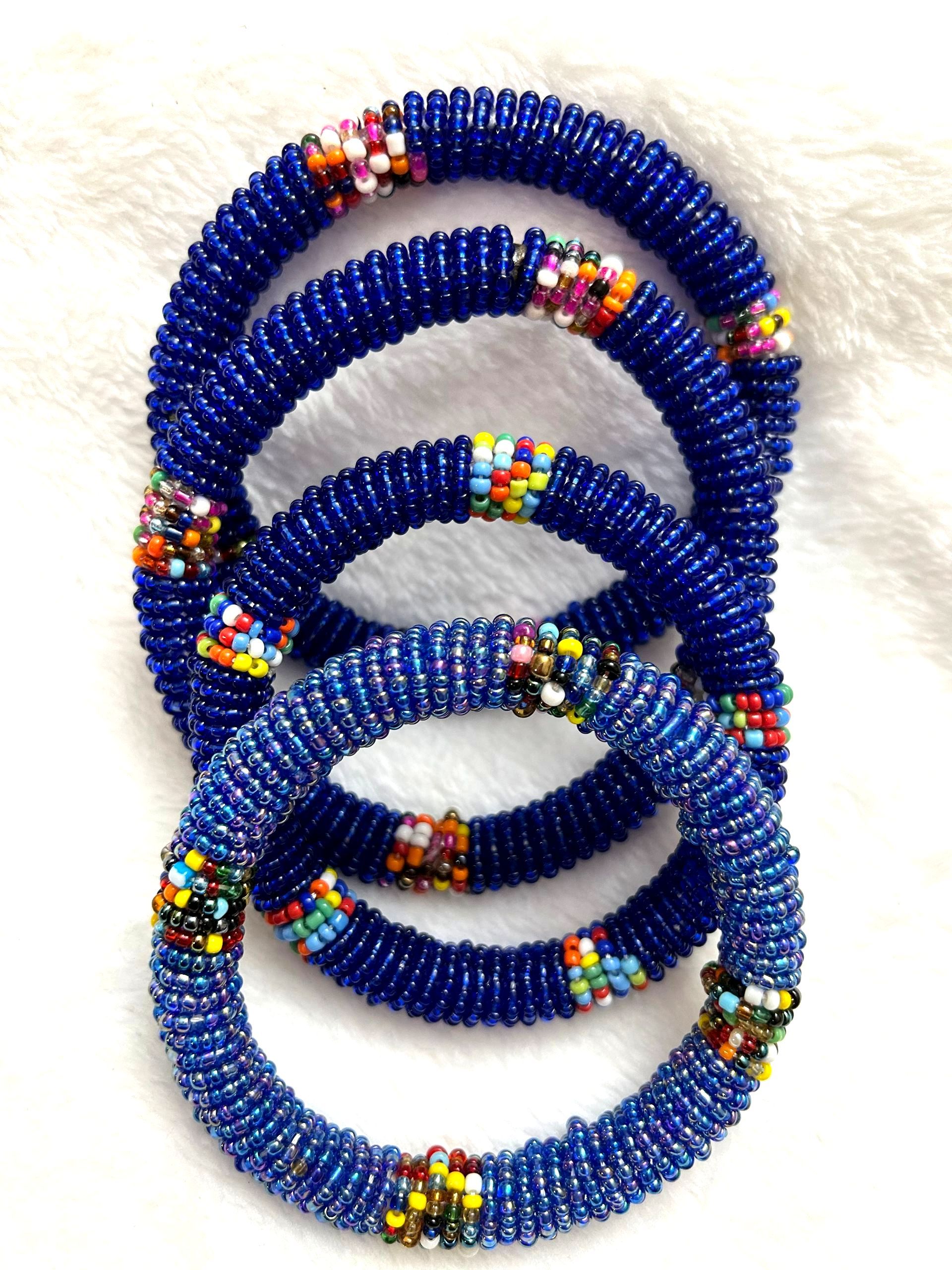 Four blue beaded bracelets stacked, each with a colorful section of beads.