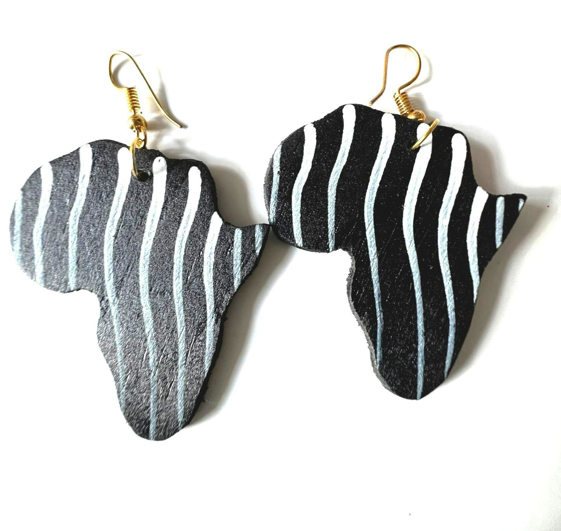 Two Africa-shaped earrings, one gray, one black, with striped patterns, gold hooks.