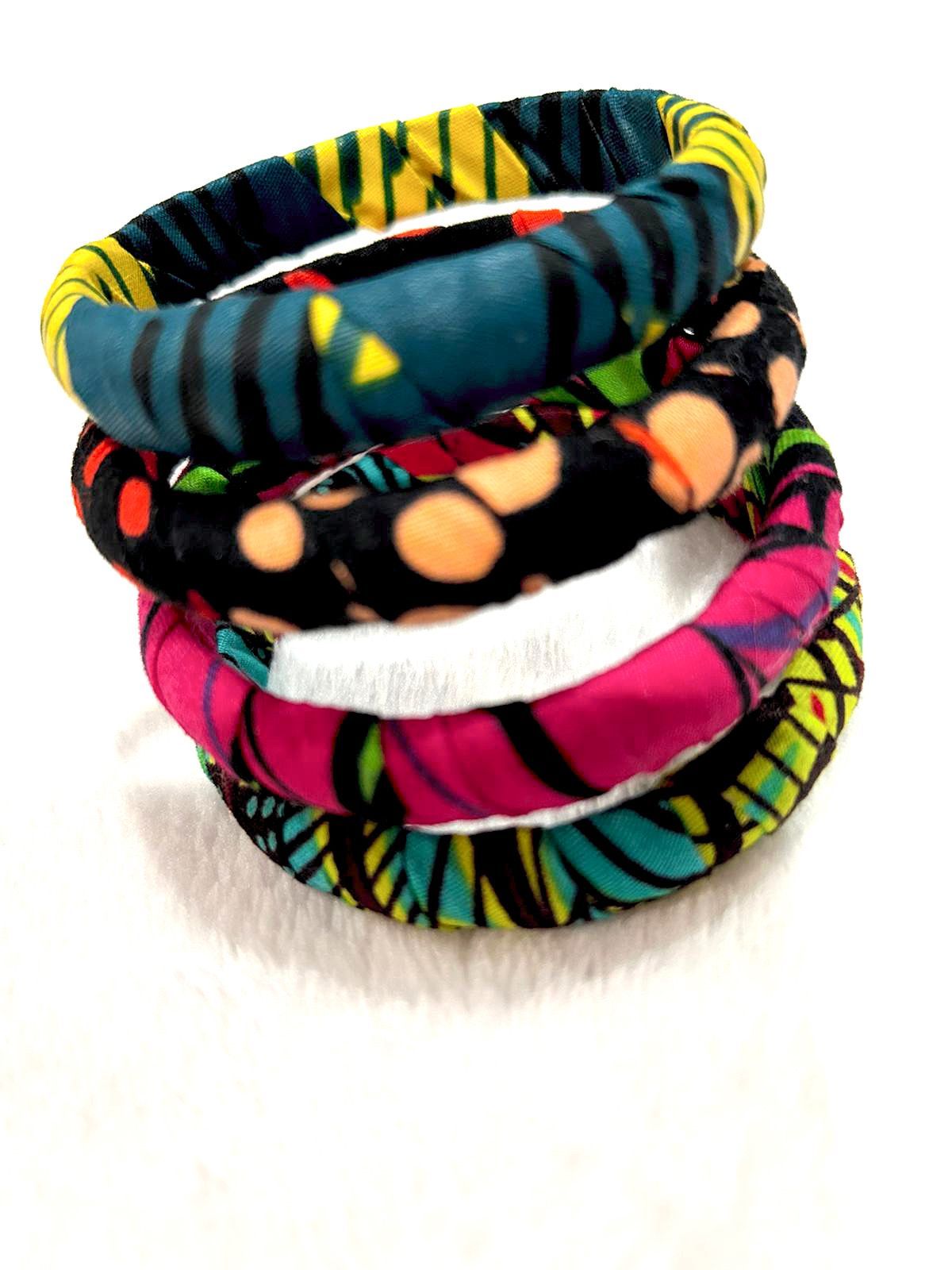 Stack of colorful fabric-covered bangles in teal, pink, black, and yellow.