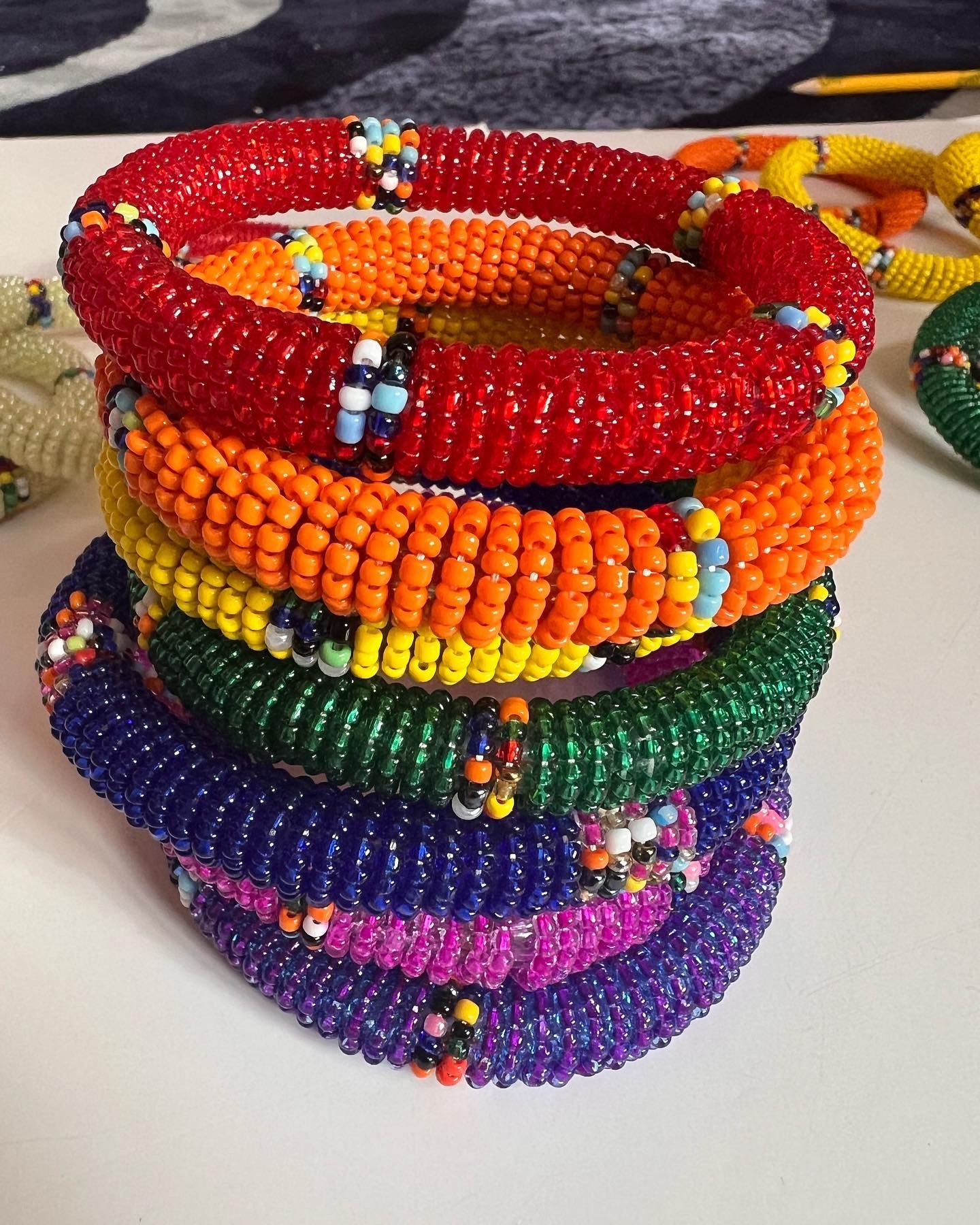 Stack of colorful beaded necklaces: red, orange, yellow, green, blue, purple, and pink.
