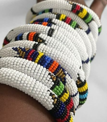 Pile of white beaded bracelets with colorful bands.