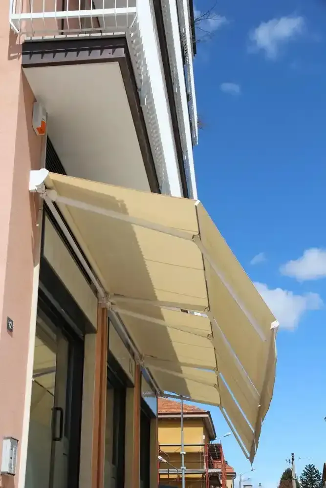 Una tenda da sole beige si estendeva sulla facciata di un edificio sotto un cielo azzurro brillante.