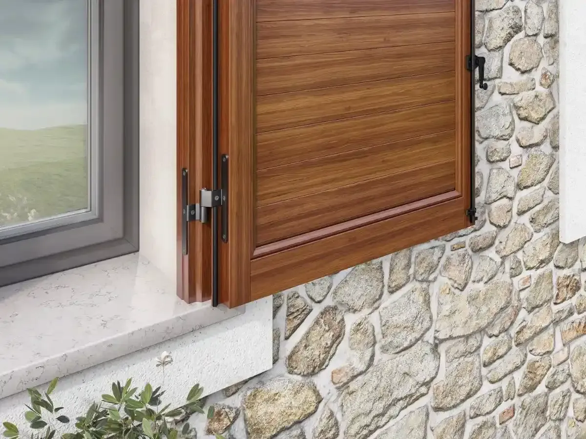 Finestra con persiane in legno incastonata in un muro di pietra accanto a un davanzale bianco.
