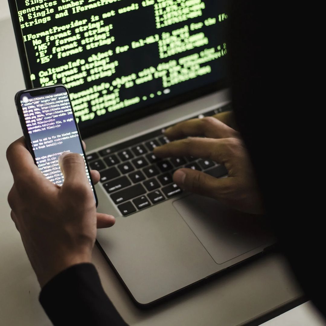Hands using phone & laptop showcasing data