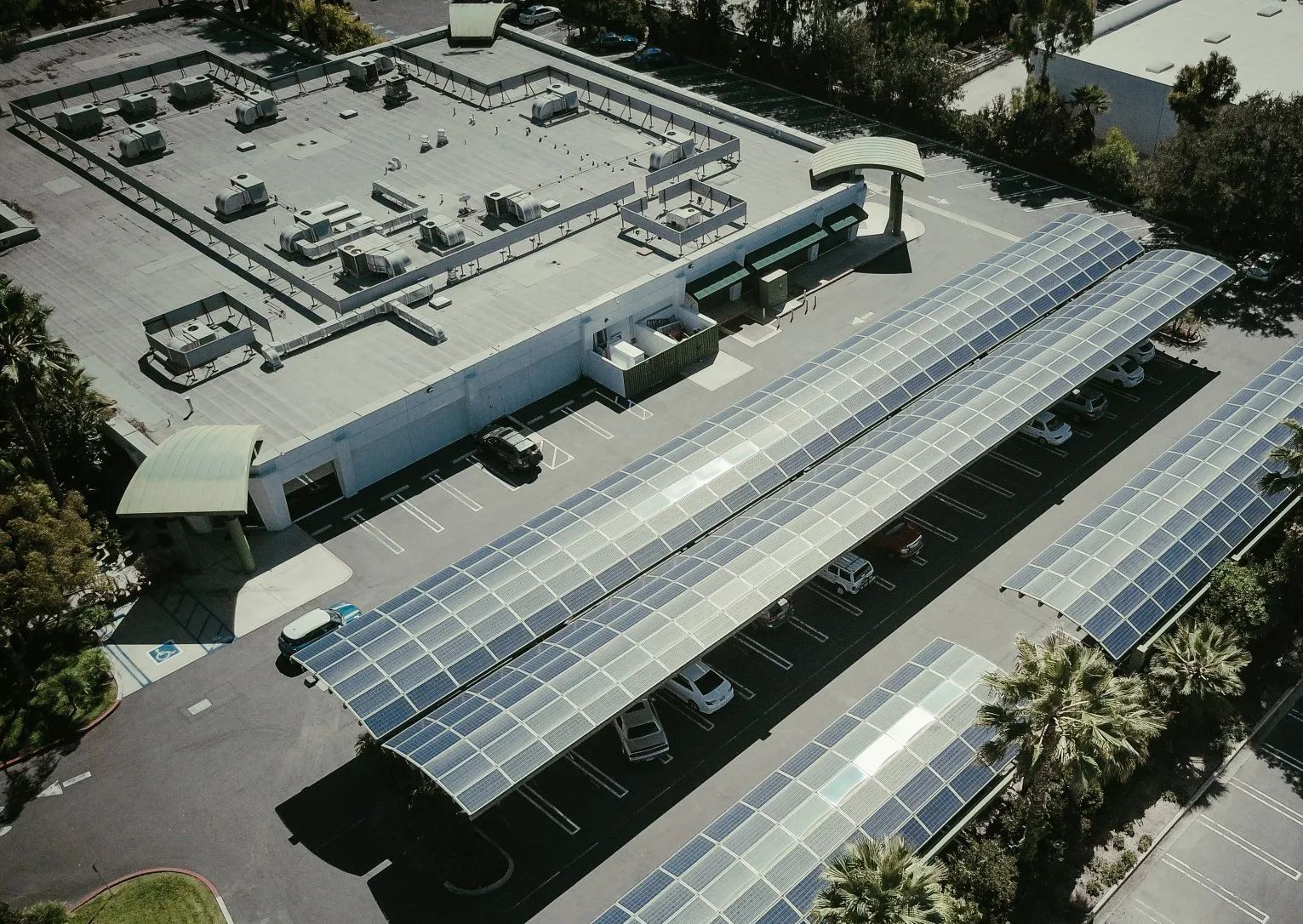 An aerial view of a parking lot with solar panels on the roof