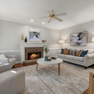 Bright living room with fireplace, gray sofas, white decor, and a ceiling fan