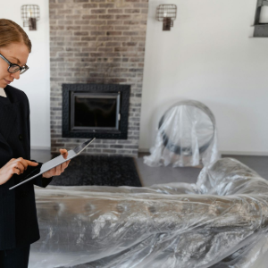 Person in a black blazer using a tablet in a plastic-covered room under renovation