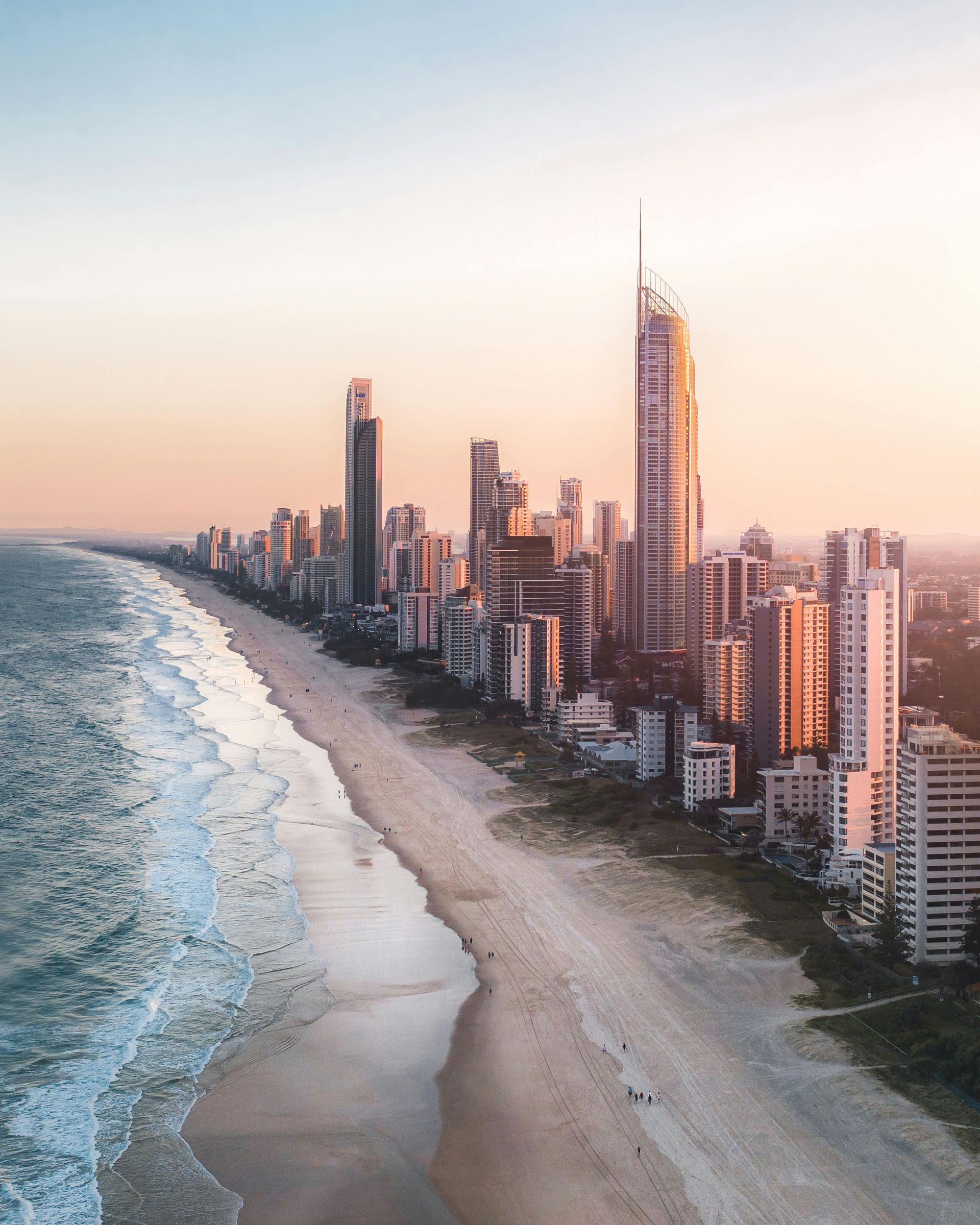 Uma vista aérea de uma praia com o horizonte da cidade ao fundo.