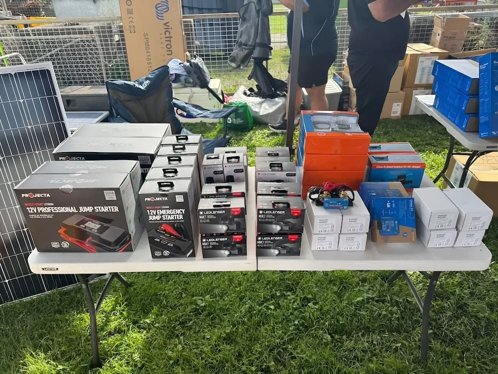 Table Display of Boxed Electronics and a Solar Panel on Green Grass — Edmonton Battery Centre in Bentley Park, QLD