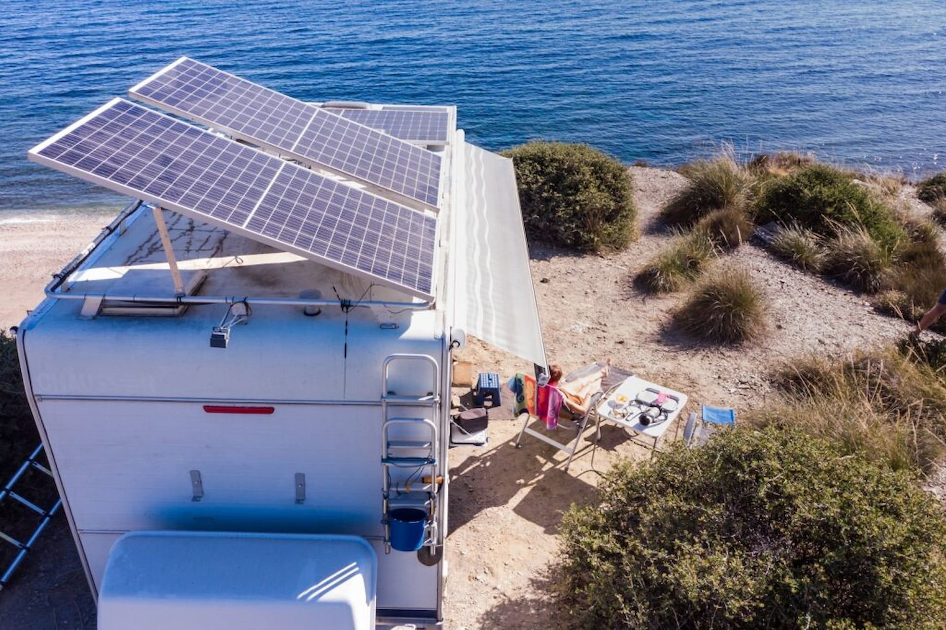 Solar Panels on a White Camper Van Parked Near the Ocean With Beach Shrubs Nearby — Edmonton Battery Centre in Edmonton, QLD
