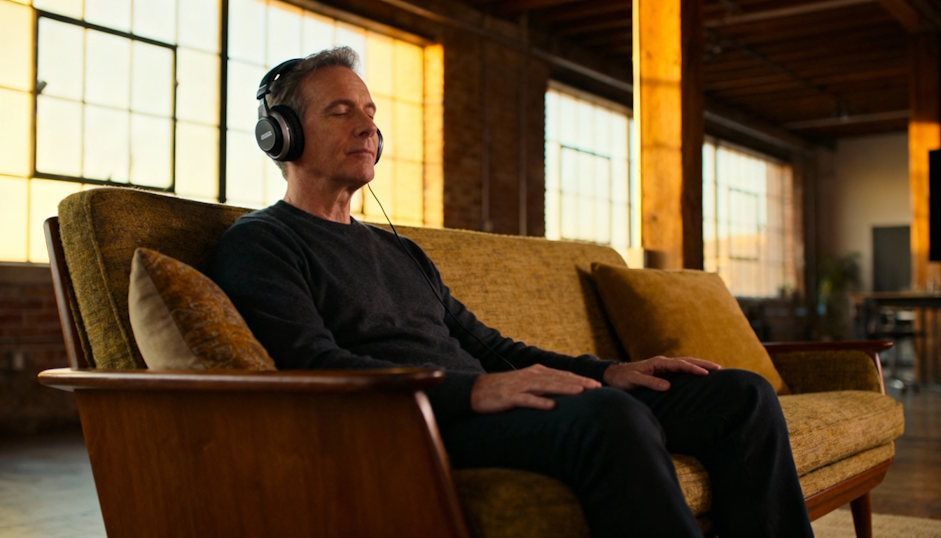 Client sitting calmly with his  headphones on during a virtual panic-hypnosis session in an Ohio City loft relaxed posture on a mid-century sofa