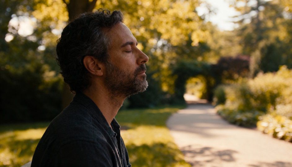 Man sitting in Cleveland Cultural Gardens pathway practicing slow breathing to calm his trauma