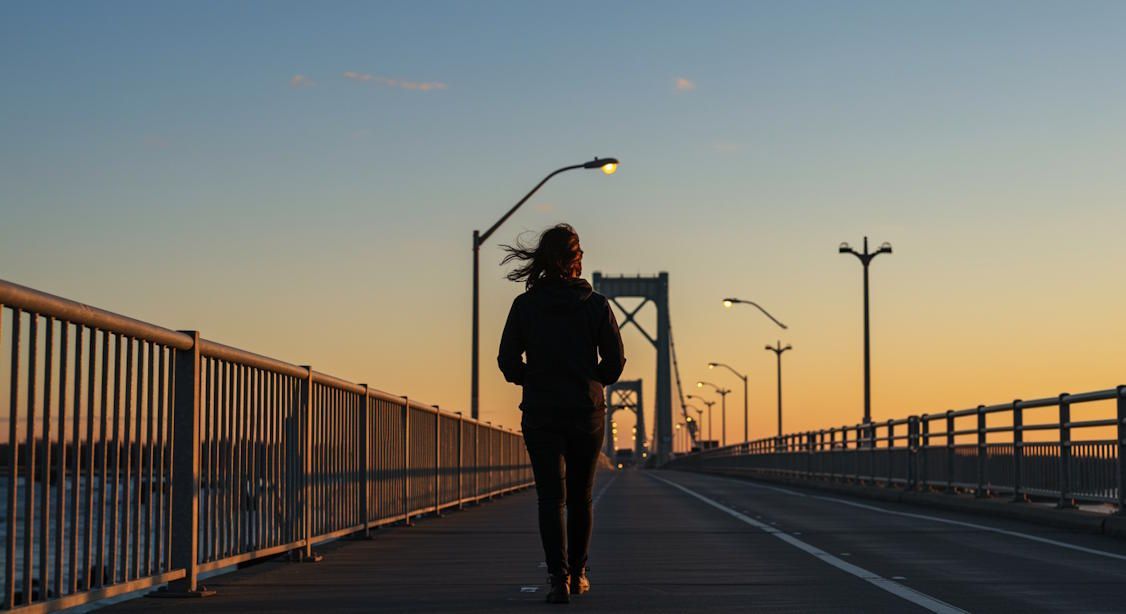Person walking across the Detroit-Superior Bridge at sunrise, confident stride