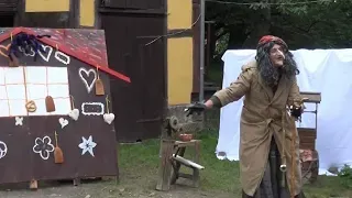 Eine Hexe steht vor einem Lebkuchenhaus.