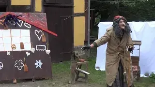 Eine Hexe steht vor einem Lebkuchenhaus.