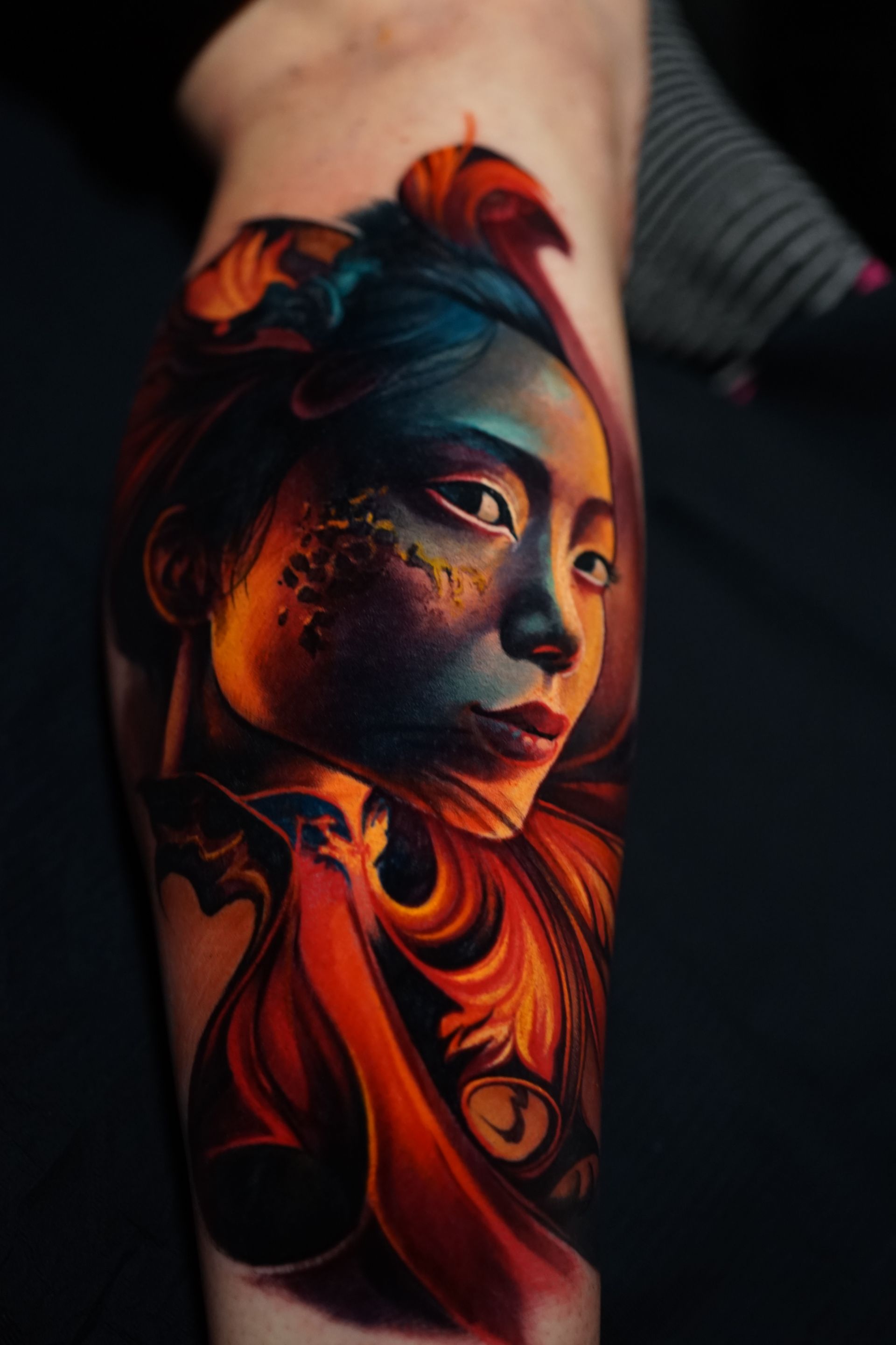 A colorful tattoo of a woman 's face on a leg.