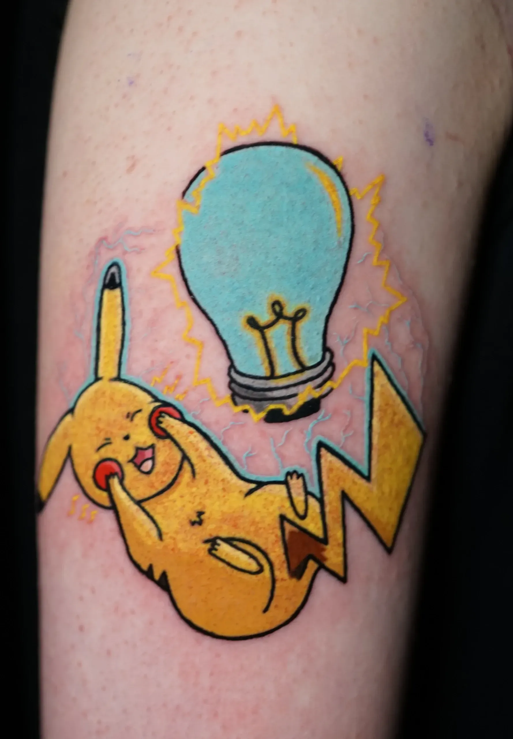 A tattoo of a pikachu and a light bulb on a person 's arm