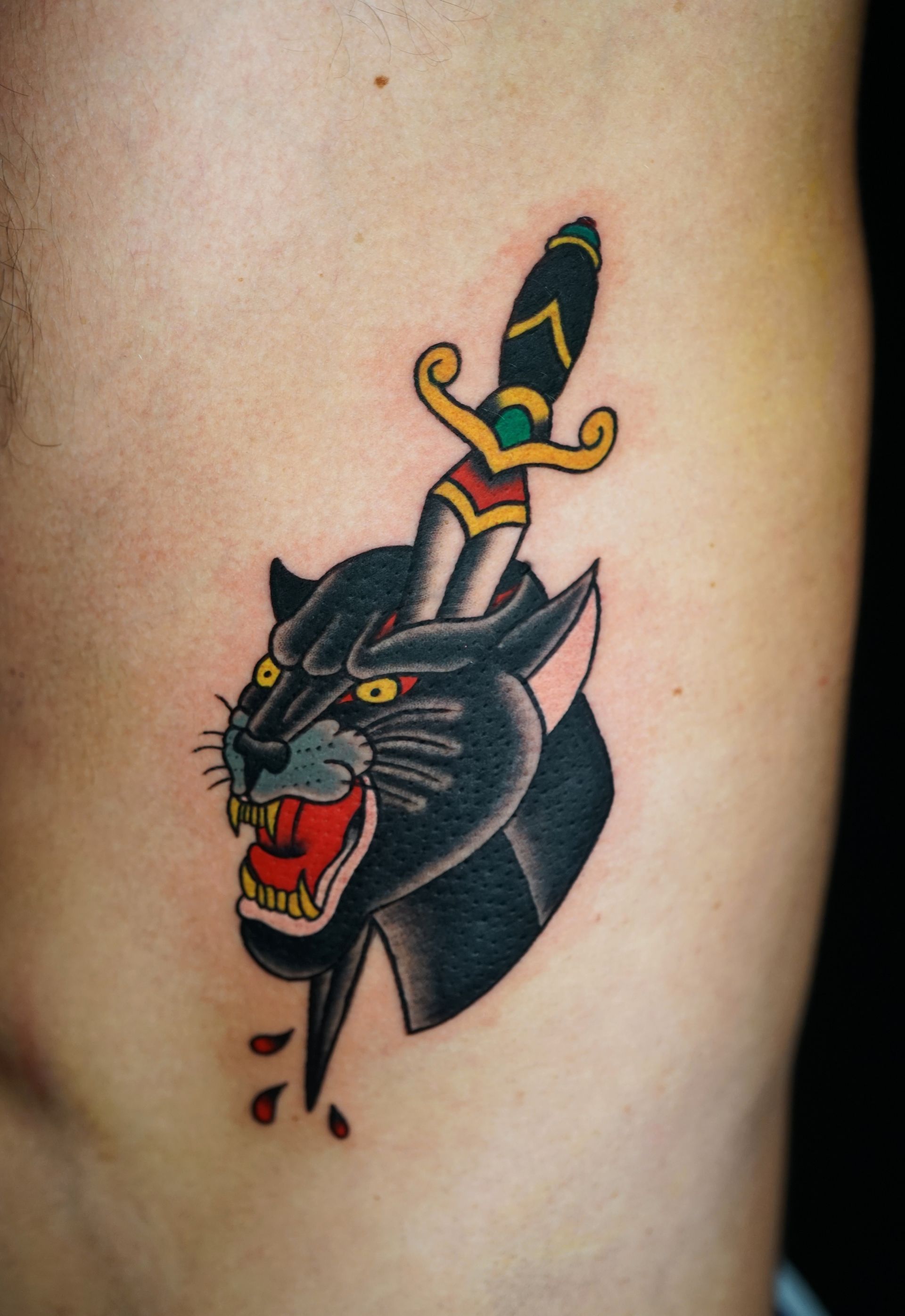 A tattoo of a panther with a dagger sticking out of its head