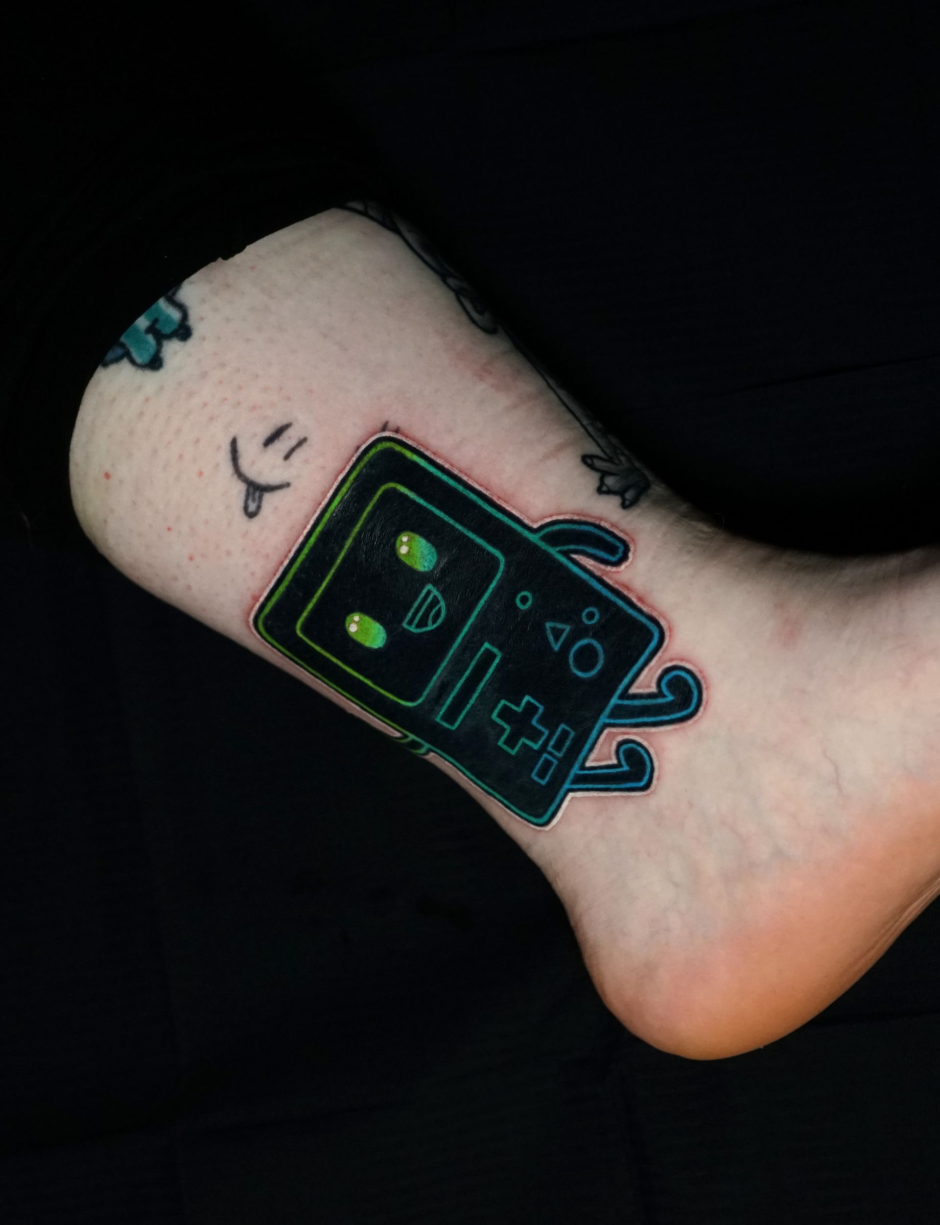 A person has a tattoo of a video game controller on their ankle.