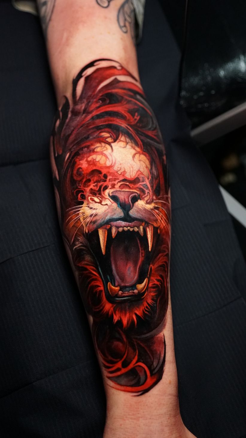 A close up of a tattoo of a lion on a person 's arm.