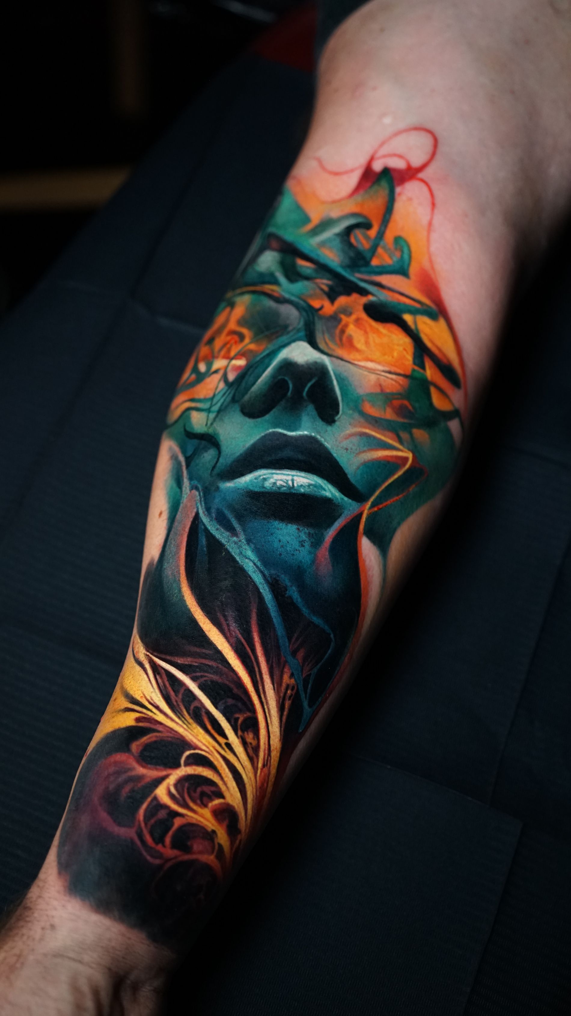 A colorful tattoo of a woman 's face on a man 's leg.