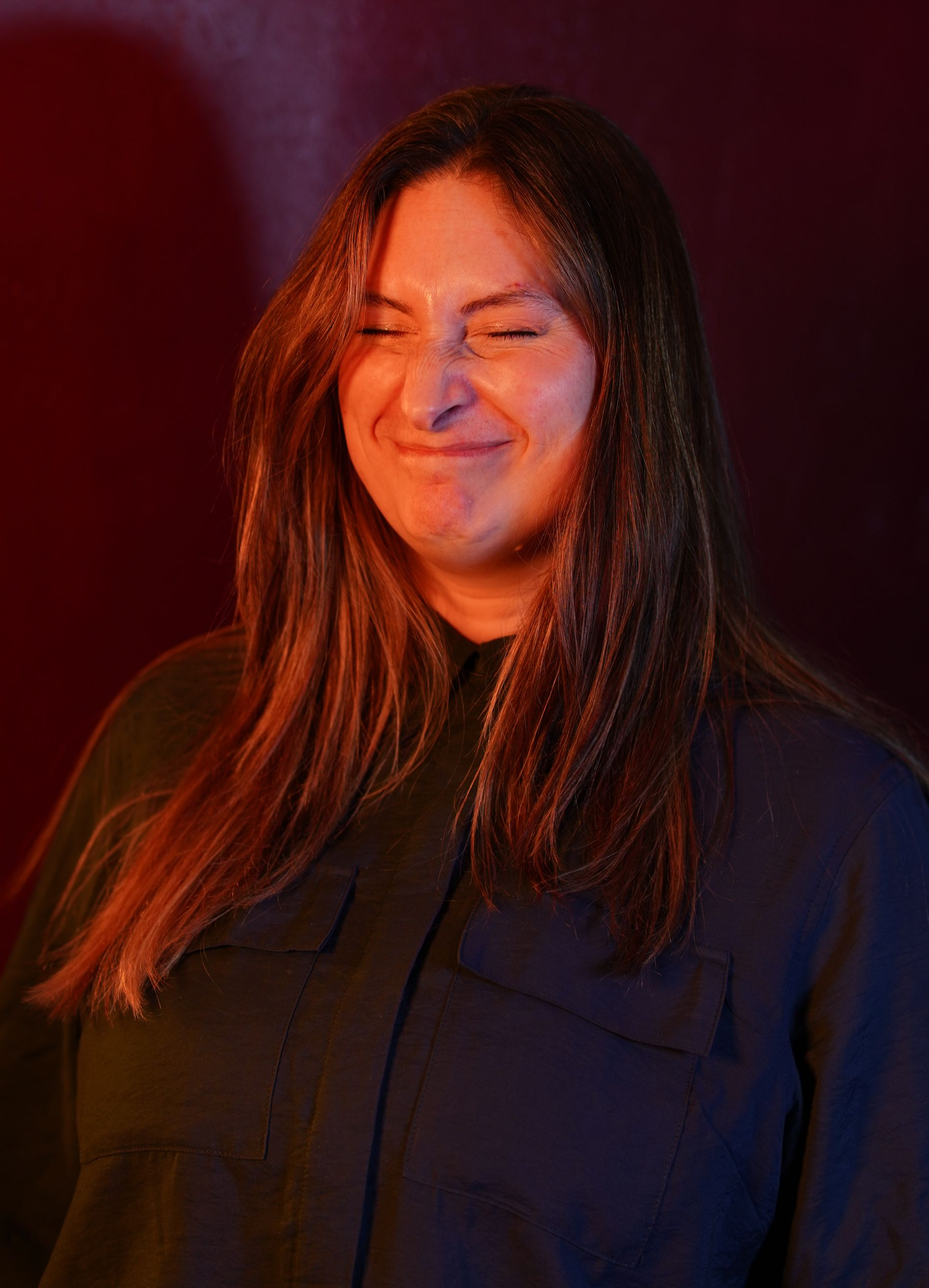A woman with long hair and a nose ring is smiling.