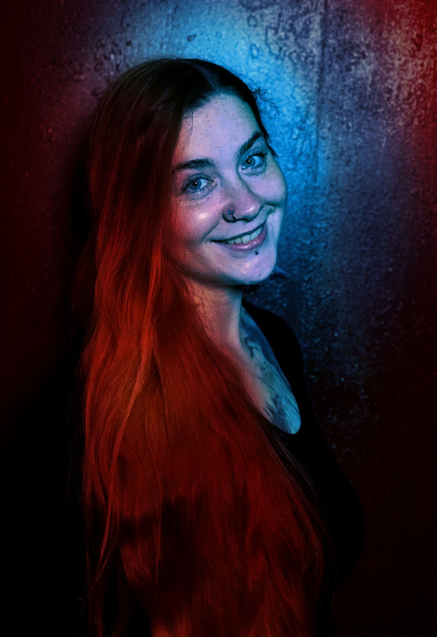 A woman with long hair and a nose ring is smiling.