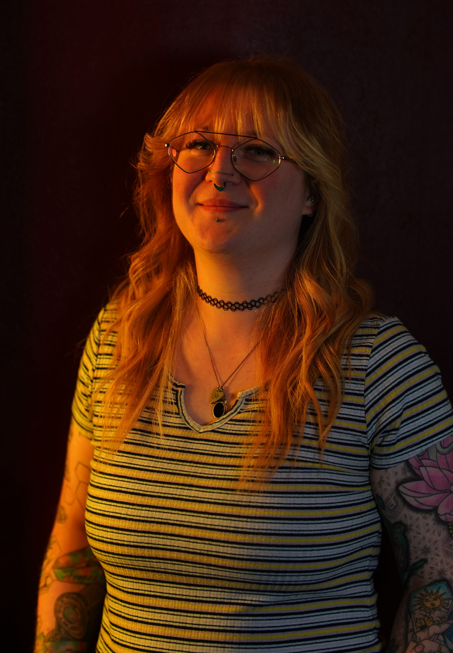 A woman with long hair and a nose ring is smiling.