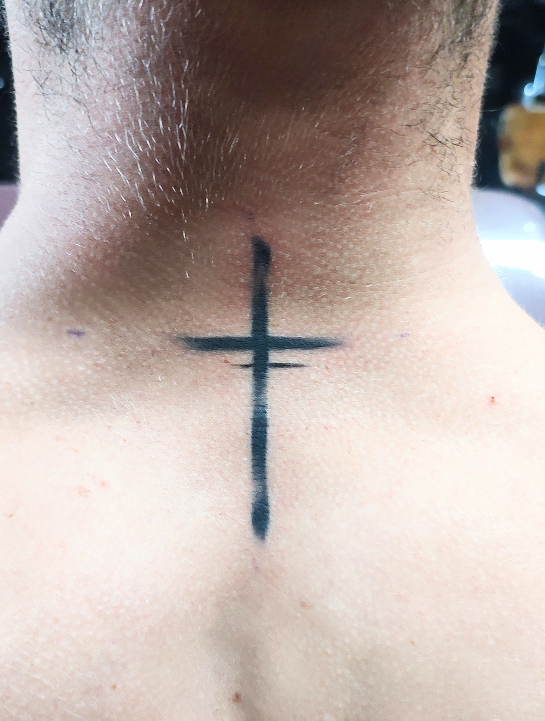 A man has a cross tattoo on his neck.