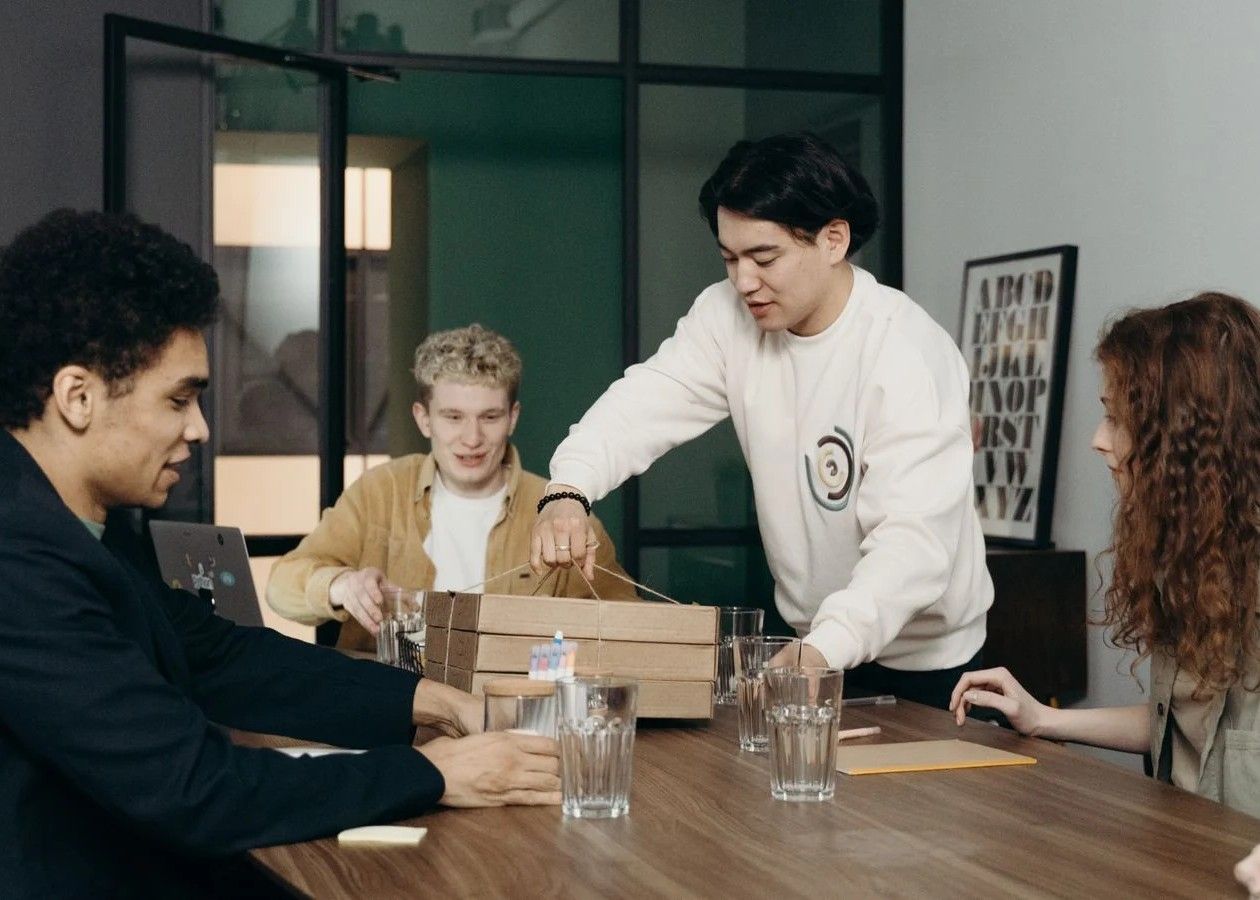 People packing a box around a wooden table in a meeting room