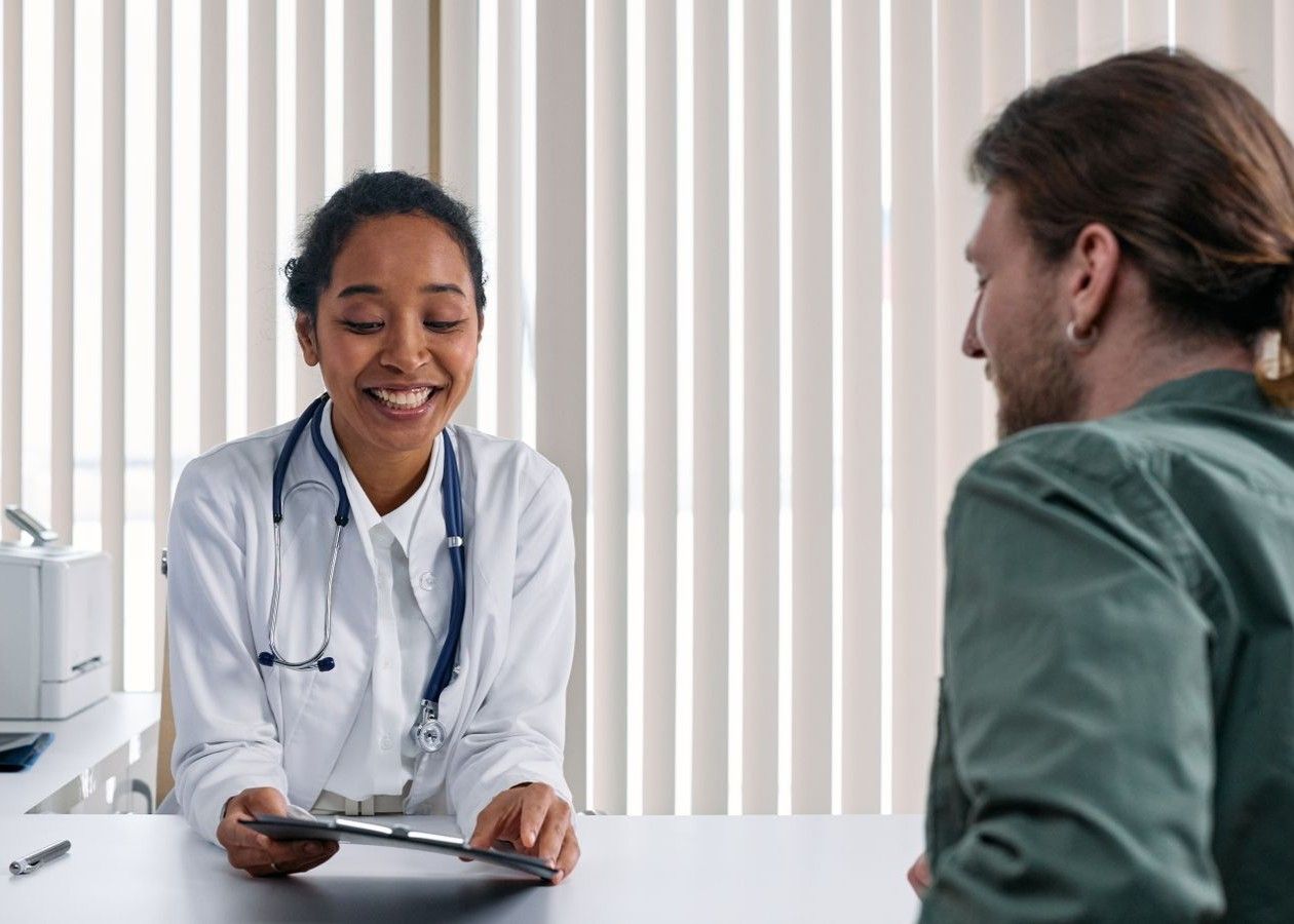 Doctor smiling and holding a tablet during a consultation with a patient in a bright office
