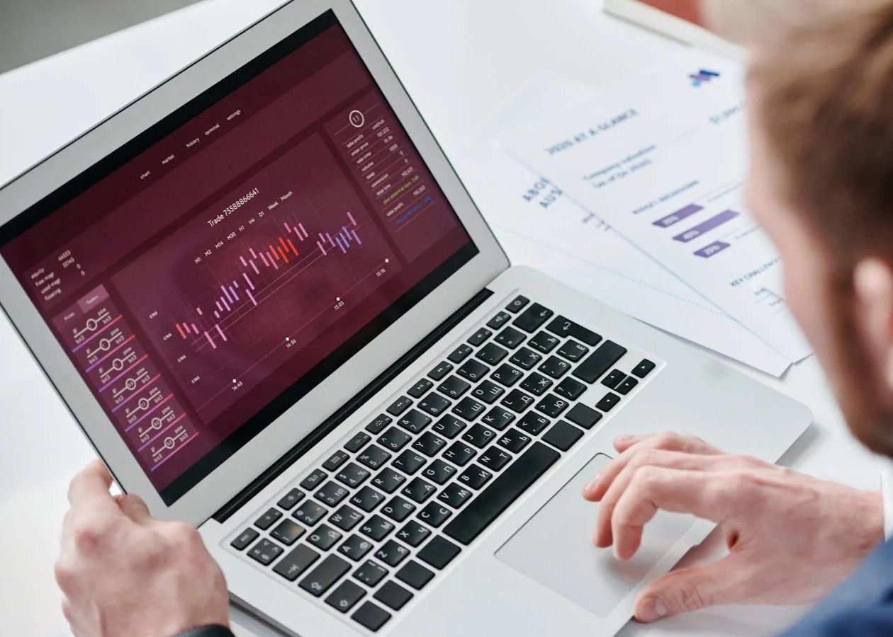 Person using a laptop with code and charts on screen in a bright workspace