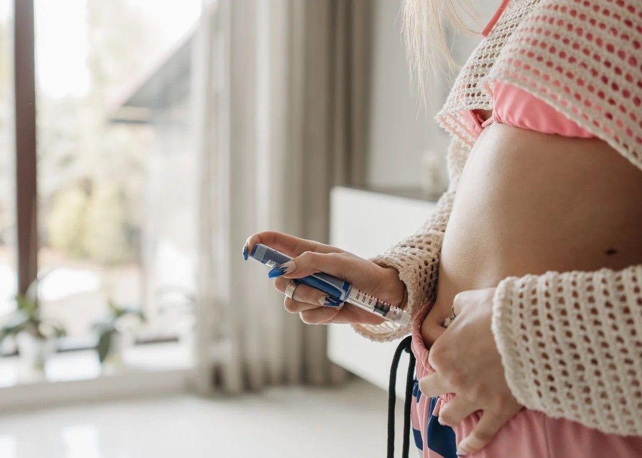 Person holding a pregnancy test with visible blue lines, standing by a bright window