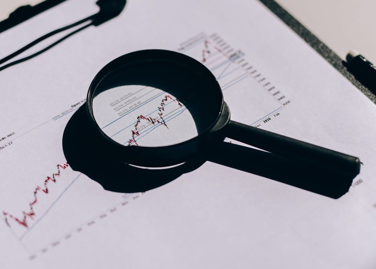 Magnifying glass over a printed financial chart with a red line graph
